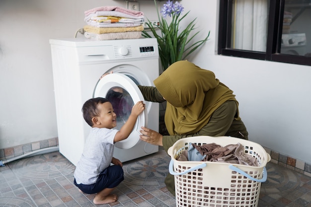 Moslimmoeder een huisvrouw met een baby die zich bezighoudt met wasgoed met een wasmachine