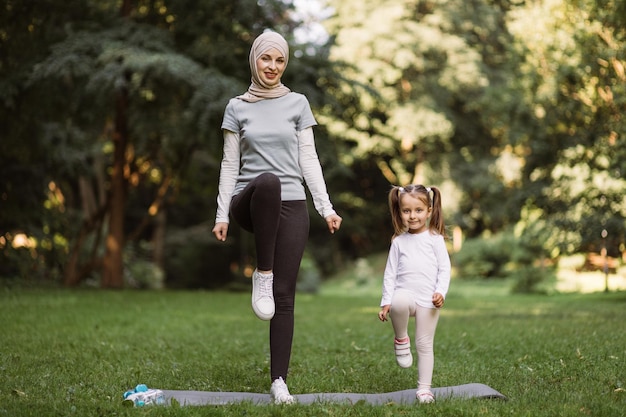 Moslimmoeder en haar dochter trainen in het park en doen hoge stappen