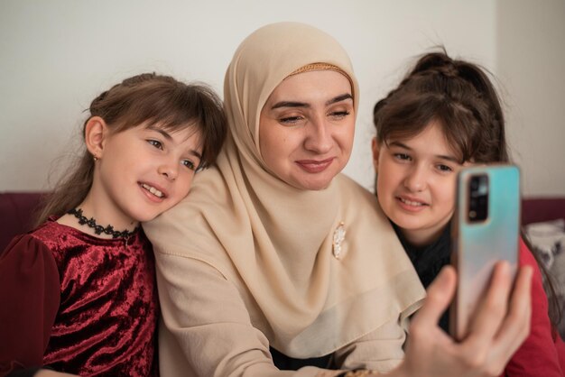 Moslimmoeder en haar kinderen bellen op een smartphone Gelukkige glimlachende moeder en dochters