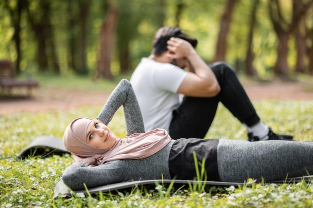 Foto moslimpaar dat op yogamat ligt en buikspieroefeningen doet