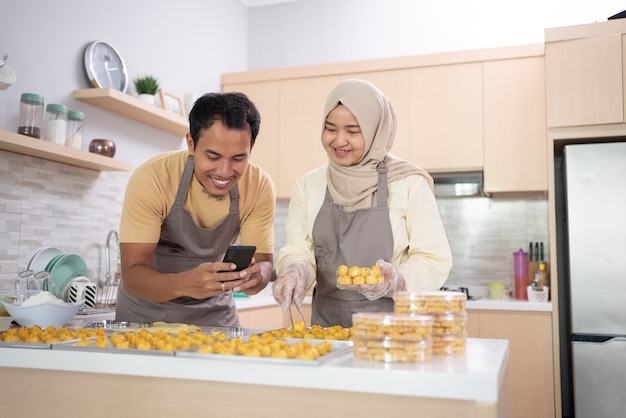 Moslimpaar gebruikt mobiele telefoon om hun snackproduct voor eid mubarak . te promoten