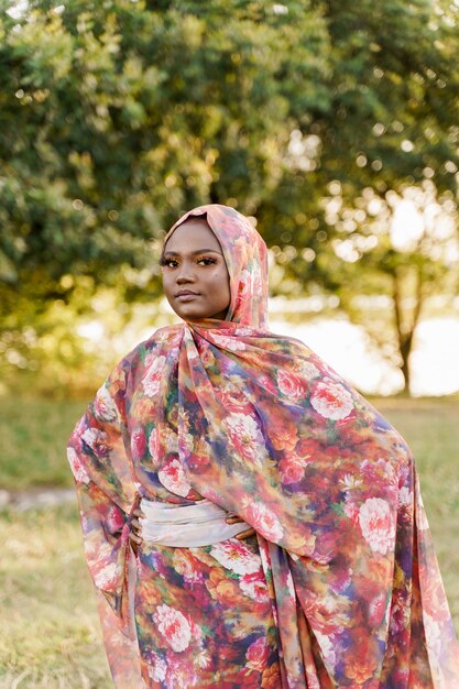 Moslimvrouw Afrikaanse etniciteit weared traditionele kleurrijke hijab op de groene weide