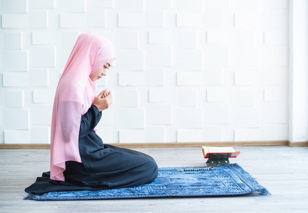 Moslimvrouw bidden op hijab binnenshuis bidden op mat
