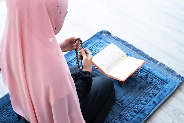 Moslimvrouw bidt met kralen en leest koran