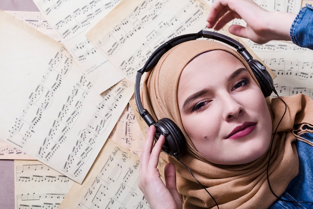 Foto moslimvrouw die aan muziek op hoofdtelefoons luistert