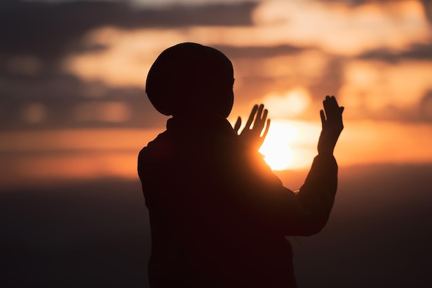 Moslimvrouw gebed met aanbidding en bidden met open handen doen dua aan Allah bij zonsondergang