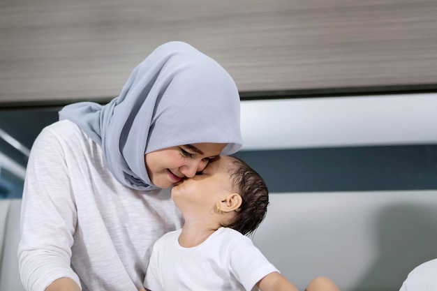 Moslimvrouw gekust door haar babymeisje op bed