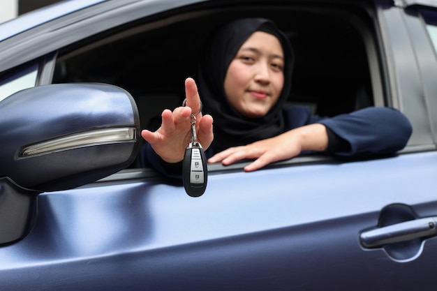 Moslimvrouw in hijab rijdt en toont autosleutels uit het raam.