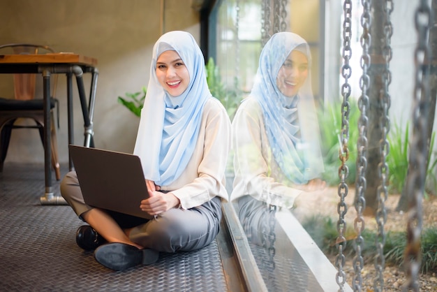 Moslimvrouw met hijab werkt met laptopcomputer in coffeeshop