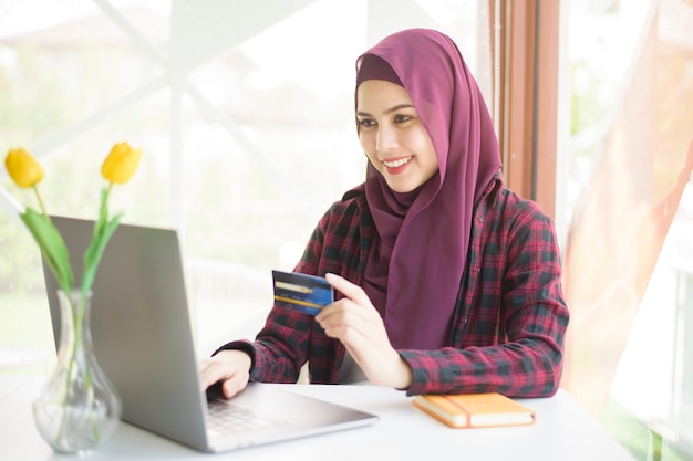 Moslimvrouw met hijab werkt met laptopcomputer in coffeeshop