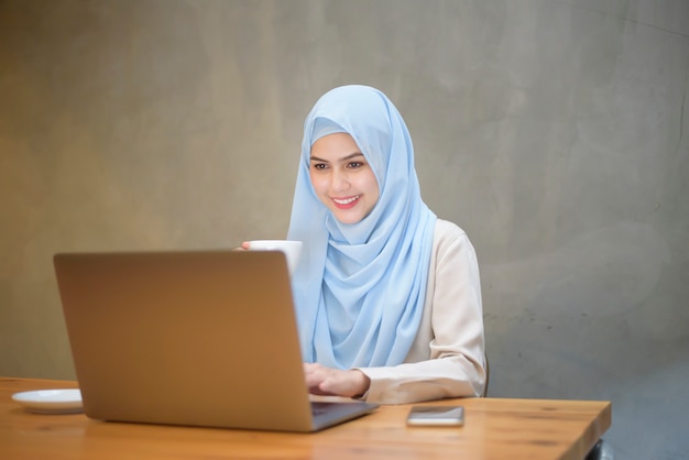 Moslimvrouw met hijab werkt met laptopcomputer in coffeeshop