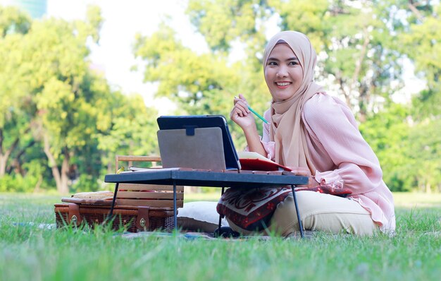 Moslimvrouw ontspannen en werken in het park op vakantie