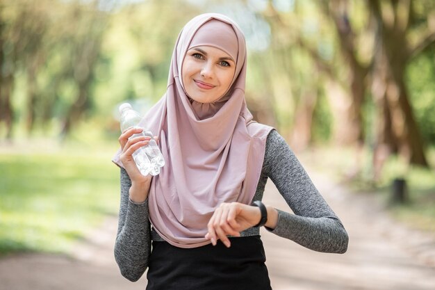 Moslimvrouw poseren in het park met slimme horloge bij de hand
