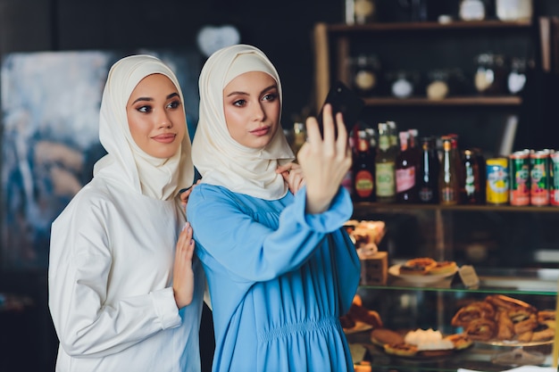 Moslimvrouw praten op mobiele telefoon in een café