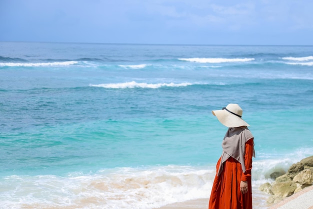 Moslimvrouw reiziger in oranje jurk met hoed loopt een wandeling maken op zomervakantie bij perf