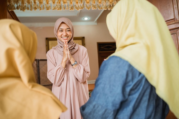 Moslimvrouw verwelkomt gasten thuis tijdens de idul fitri-viering