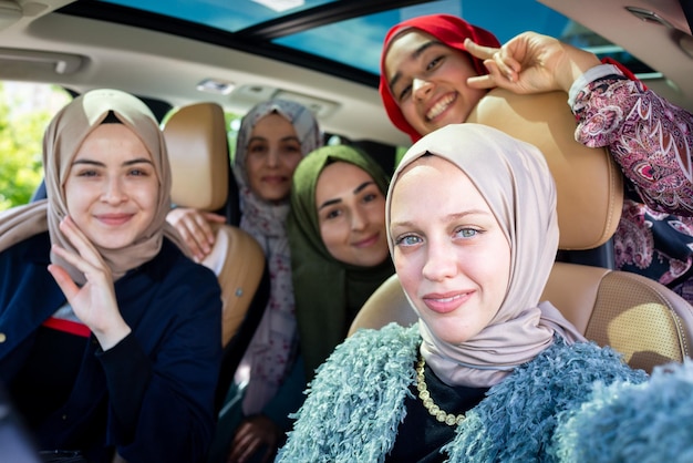 Moslimvrouwelijke vrienden genieten van een roadtrip op vakantie in de auto. Foto van hoge kwaliteit