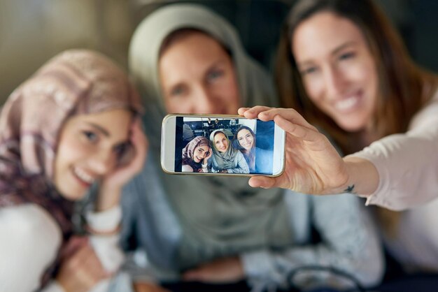 Foto moslimvrouwen vrienden en selfie met telefoonglimlach en geluk voor post op blog-app of sociaal netwerk gelukkige islamitische vrouwengroep en smartphone voor fotografie profielfoto en geheugen op web