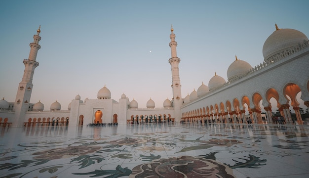 A mosque in the evening with a moon in the sky