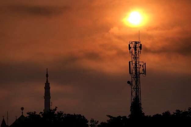 mosque minaret and communication tower during sunrise radio frequency transmission tower