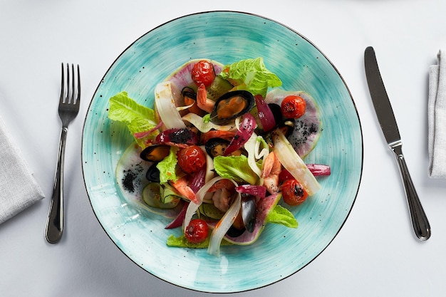 Mosselen vongole met salade mosselen gekookt in witte wijnsaus mossel voorgerecht met bestek op een lichte achtergrond bovenaanzicht