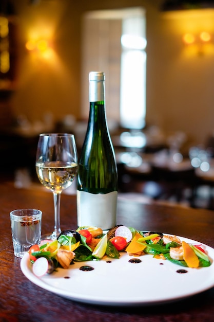 Mosselsalade op een witte plaat met glas en fles wijn op de achtergrond van de bar Concept een mooi gerecht dat voor een restaurant dient