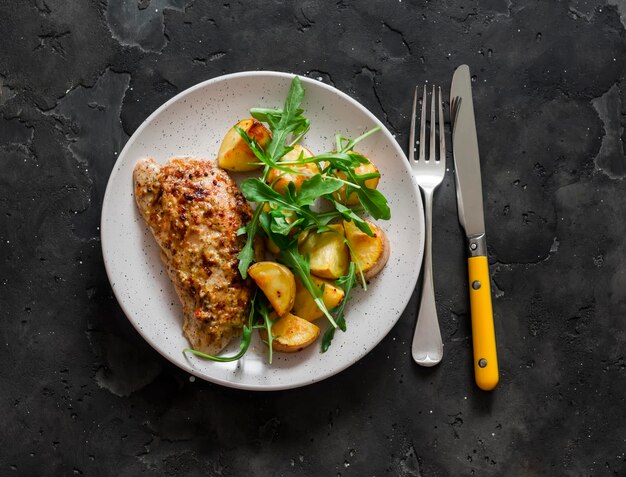 Mosterd griekse yoghurt marinade geroosterde kalkoen en nieuwe aardappelen rucola salade op een donkere achtergrond bovenaanzicht