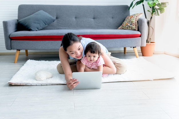 Mother and 7 month old daughter sitting on the floor and looking at a tablet