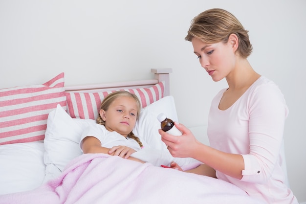 Mother about to give medicine to sick daughter