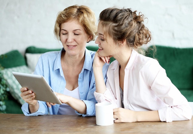 Mother and adult daughter using tablet computer at home