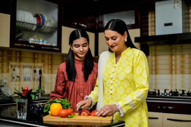写真 母と愛らしい娘がキッチンでリンゴを切るインドのパキスタンモデル