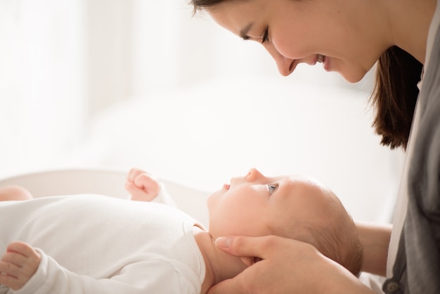 写真 ベッドの上の母と子。日当たりの良い寝室で遊んでいるおむつのママと男の子。