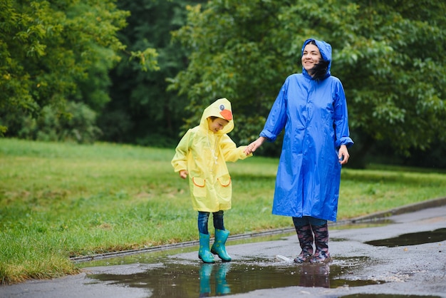 写真 母と子が雨の中で遊んで、ブーツとレインコートを着ている