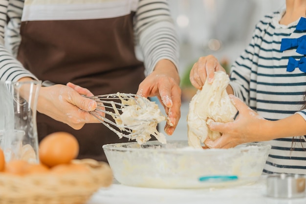 写真 母と子が一緒に働いて、家庭の台所でパン屋の料理とベーキングのために小麦粉と材料を混ぜ合わせます