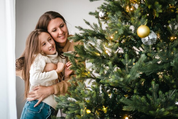 写真 家のリビングで一緒にクリスマスツリーを飾っている母と娘