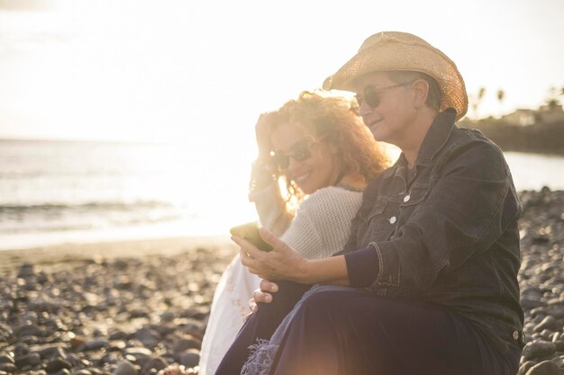 写真 母と娘が海に逆らって携帯電話を見ている