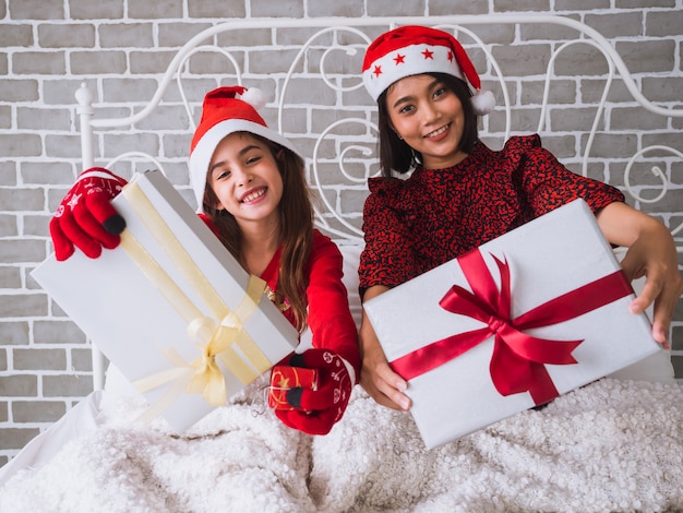 写真 母と娘のギフトボックスを表示し、ベッドの上のクリスマスを祝う