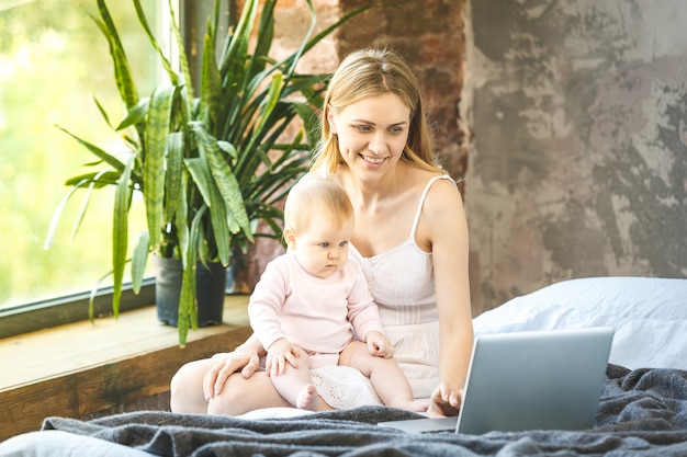 写真 母と自宅で彼女の小さな赤ちゃん。ノートパソコンで何かを見ている彼女の赤ちゃんと母親。