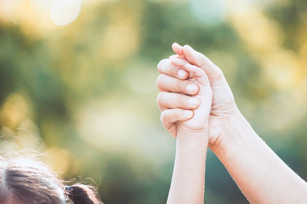 写真 母親と小さな子供の女の子一緒に公園で育った手を保持