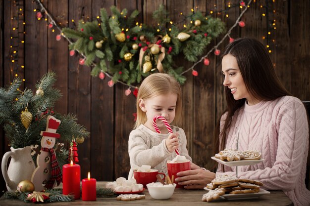 母と自宅のクリスマスクッキーを持つ少女