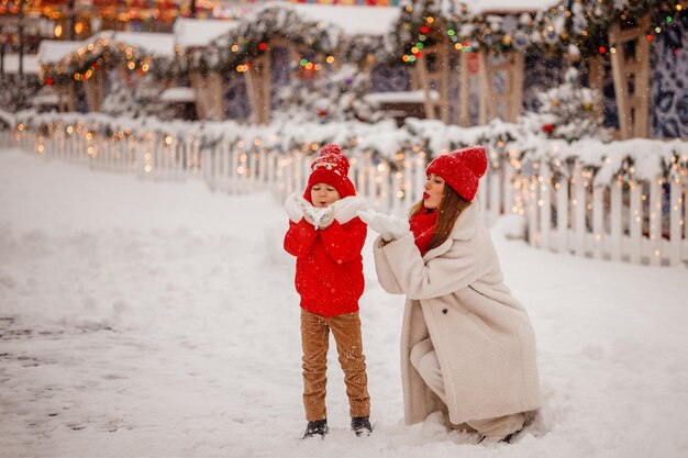 写真 暖かい服を着た母と息子は、モスクワの赤の広場で雪が降る新年のフェアで冬を楽しんでいます