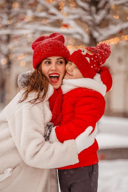 写真 暖かい服を着た母と息子が雪の降る新年のフェアで冬を楽しむ