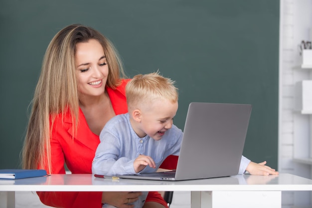 어머니와 아들이 함께 컴퓨터 노트북을 사용하여 어머니와 함께 노트북을 사용하는 작은 학교 아이 아들이 가르칩니다.