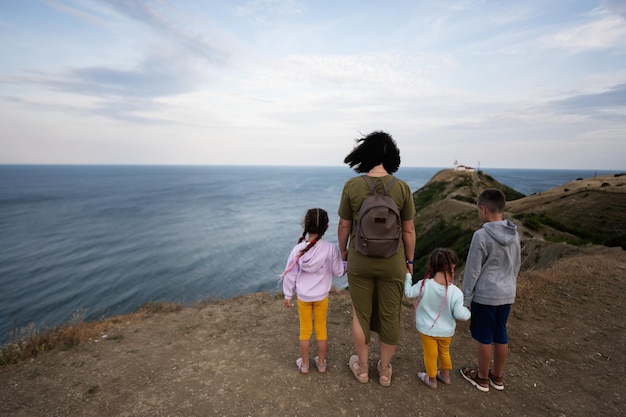 사진 바다 를 바라보는 산 꼭대기 에 서 있는 어머니 와 세 자녀