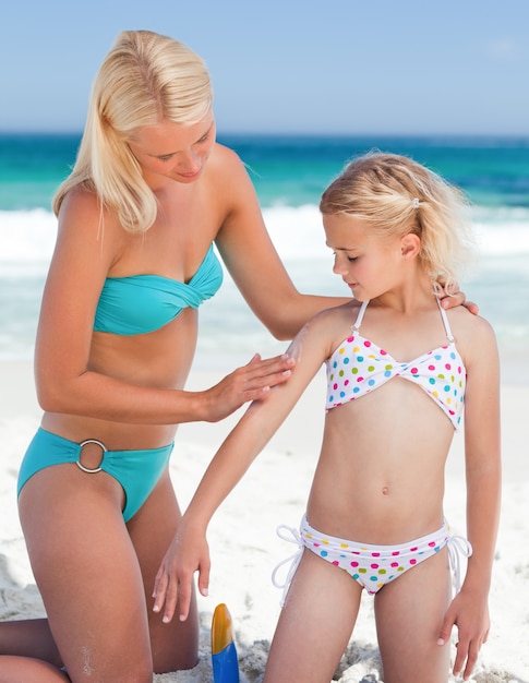 Photo mother applying sun cream on her daughter's back