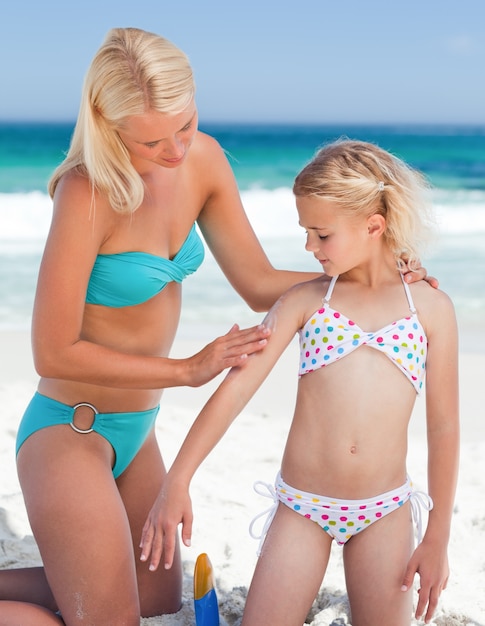 Mother applying sun cream on her daughter's back