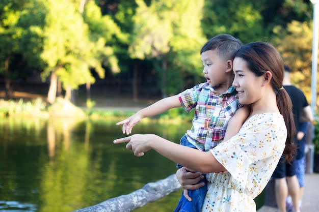 Foto la mamma e il bambino sono felici, sorridenti, godendo l'aria calda e pura in un bellissimo giardino.