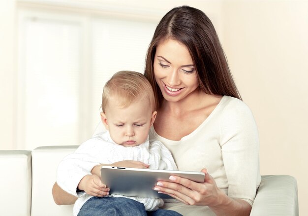 mother and baby are looking to play and read tablet computer on the couch at home