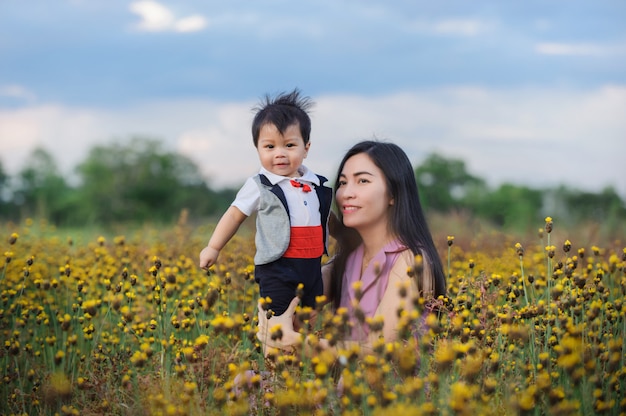 夏の日に黄色の芝生のフィールドで母親と赤ちゃんの男の子。