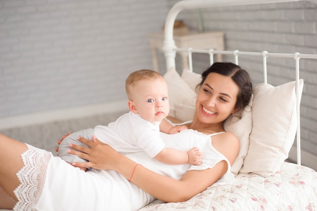 Una madre e un bambino bambino su un letto bianco.